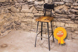Bar stool with walnut wooden top and back close to a massive brick wall