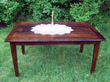 Wormy chestnut table with a candle on top in the back yard