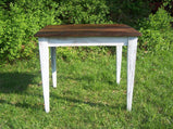 Wormy chestnut coffee table with white legs and walnut top in a garden