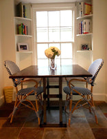 Reclaimed wood dining table in a room with two chairs close to a window