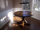 Round dining table made of reclaimed wood in a room with shaded sunlight