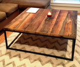 Square coffee table with reclaimed wooden top and square metal legs close to a sofa